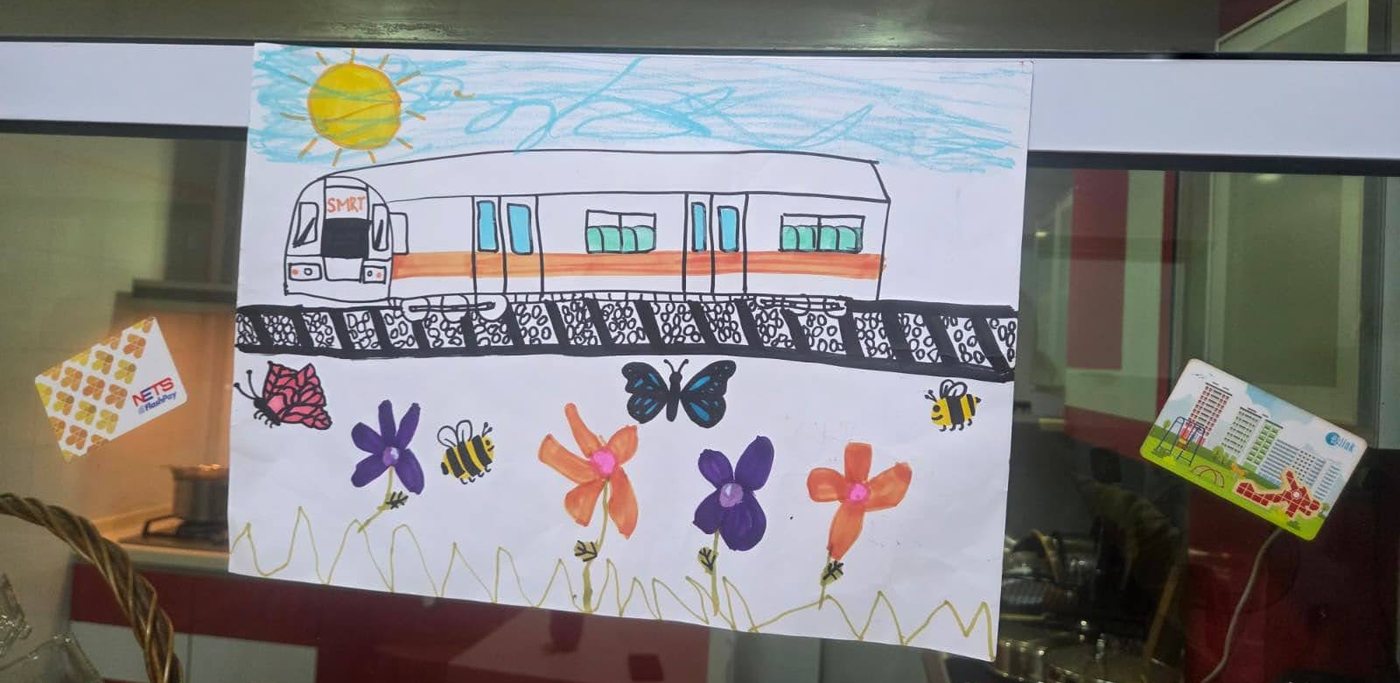 A colourful drawing of an SMRT train on its tracks, with a sun, flowers, butterflies and bees